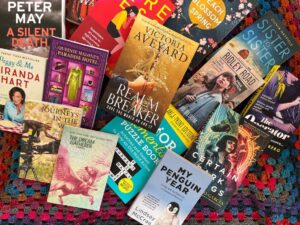 A range of books from Hachette Australia scattered on top of a hand-knitted blanket from Knit4Charities